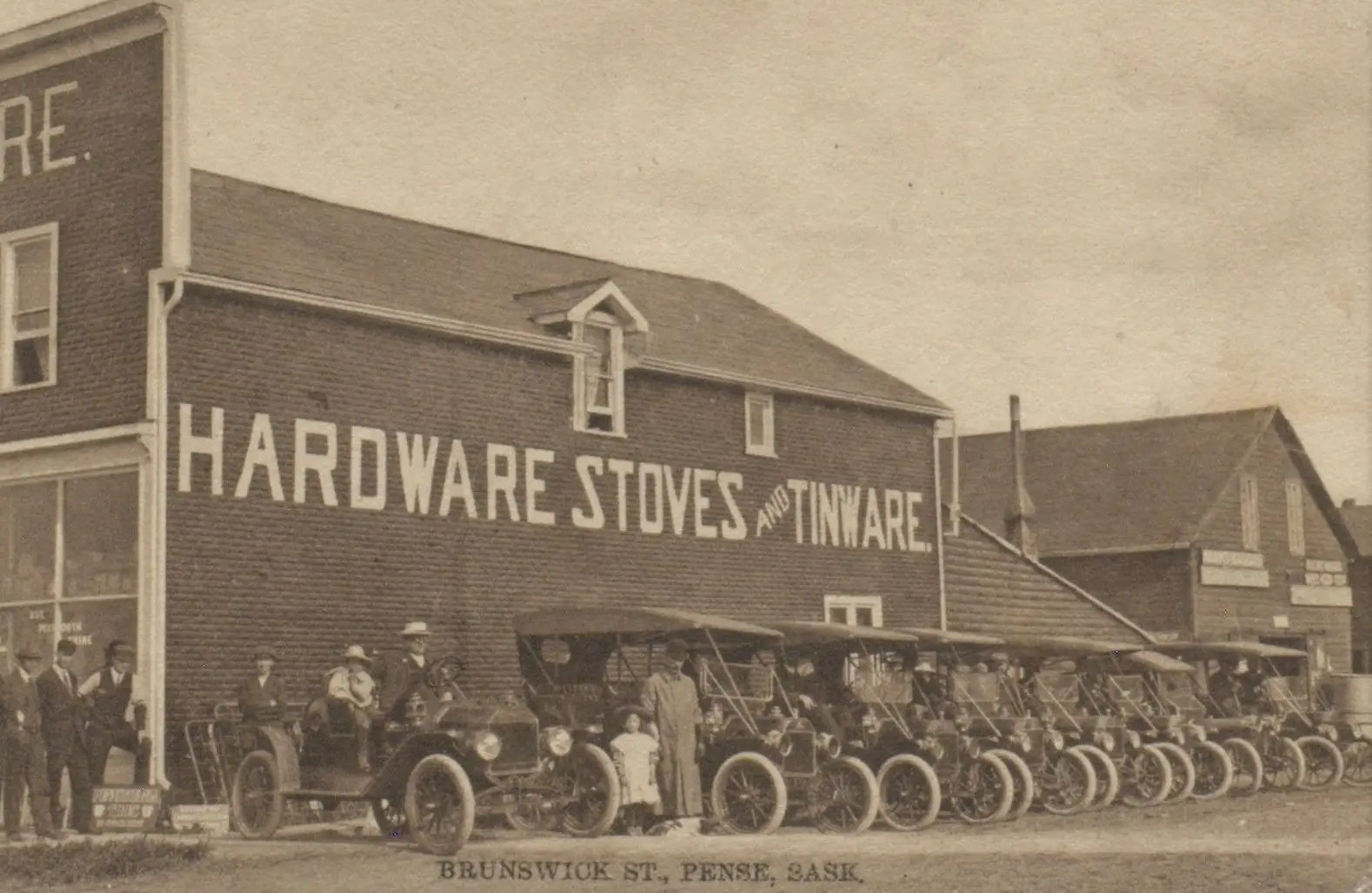 Brunswick Street with row of automobiles outside the hardware store
