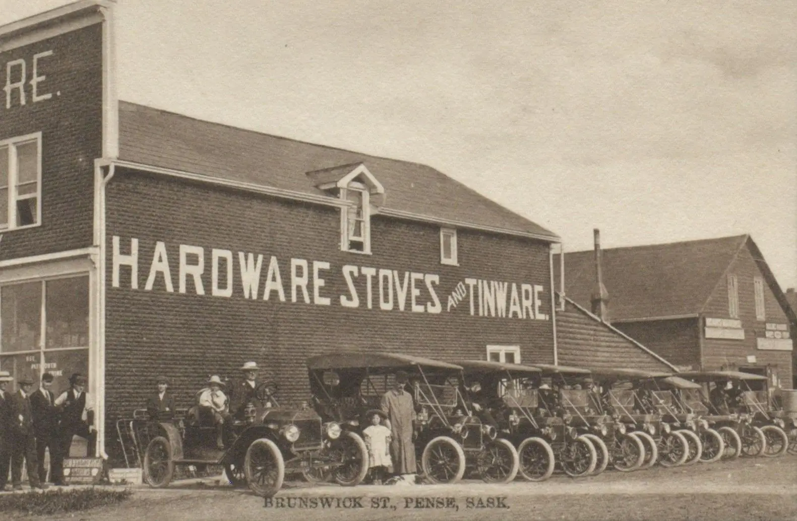 Brunswick Street with hardware store and row of early automobiles