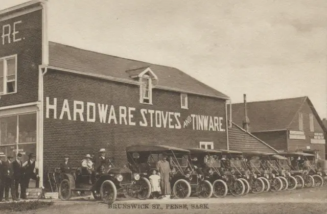 Brunswick Street with hardware store and row of early automobiles